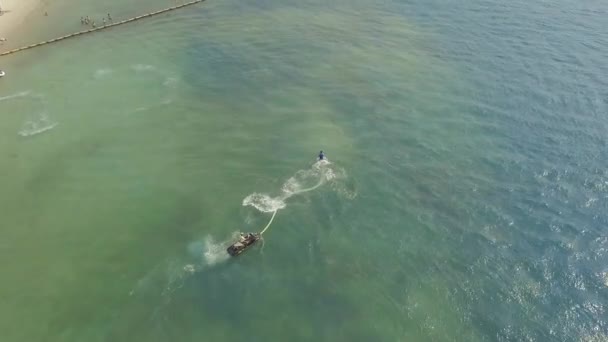 Jeune homme chevauchant à bord de la mouche avec jet d'eau pulvérisation sur l'eau de mer bleue. Pilote à bord en pleine mer. Sport nautique pendant les vacances d'été. Sport aquatique. Activité estivale .