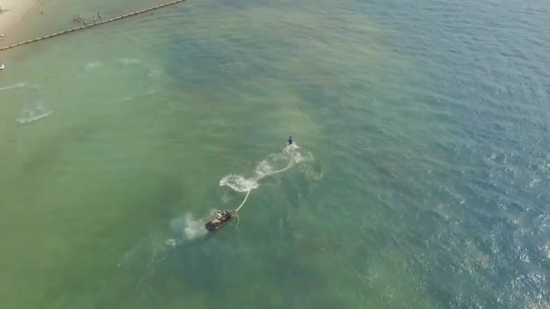 Young man riding on fly board with water jet spray over blue sea water. Fly board rider in open sea. Water sport at summer vacation. Aquatics sport. Summer activity. — ストック動画