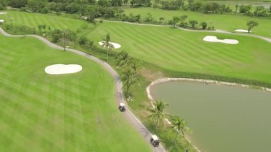 Golfçü uçan drone yeşil golf sahası üst görünümünde. Golf kulübü, araba ve göl manzara yeşil alanda havadan görünümü insanlar. Spor ve hobi kavramı.