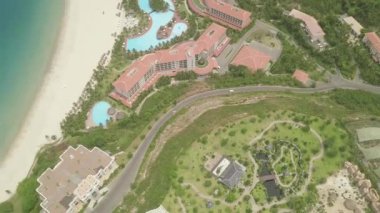 Deniz kıyısında ki yüzme havuzuna sahip lüks tatil oteli. Uçan drone yukarıdan mavi su manzaralı kumlu deniz plajında turistik otelde büyük yüzme havuzu.