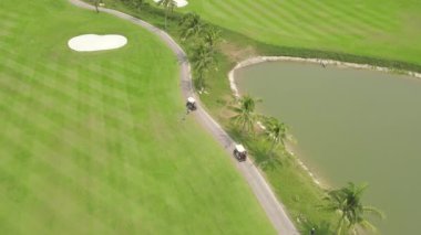 Golfçü uçan drone yeşil golf sahası üst görünümünde. Golf kulübü, araba ve göl manzara yeşil alanda havadan görünümü insanlar. Spor ve hobi kavramı.