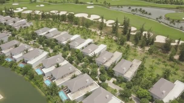 Luxury cottage village and green golf courses with lake aerial landscape. Top view from drone golf club with green field, lake, mansion and villas in luxury village. — Stock Video