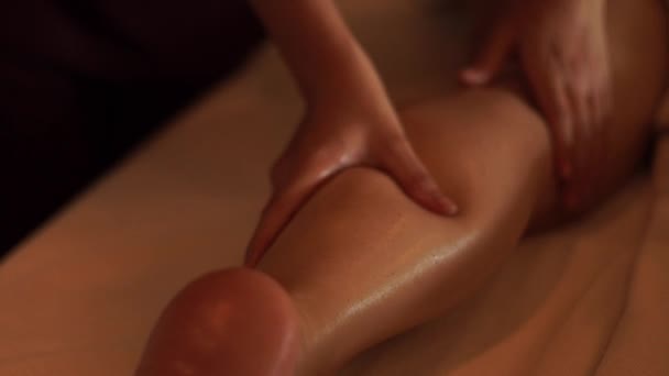 Masseur fazendo massagem pernas com óleo para a jovem mulher no salão de spa resort. Jovem mulher recebendo massagem corporal no centro de spa de luxo. Relaxamento corporal e cuidados com a pele . — Vídeo de Stock