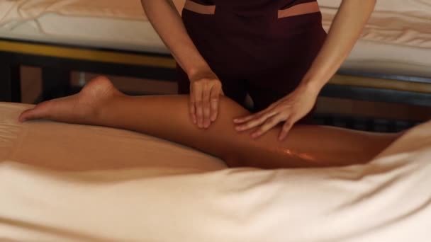 Masseur fazendo massagem pernas com óleo para a jovem mulher no salão de spa resort. Jovem mulher recebendo massagem corporal no centro de spa de luxo. Relaxamento corporal e cuidados com a pele . — Vídeo de Stock