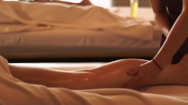 Genç bir kadın spa salonunda yağ ile bacak masajı yaptırıyor. Genç bir kadın lüks kaplıca merkezinde vücut masajı yaptırıyor. Vücut gevşemesi ve cilt bakımı.