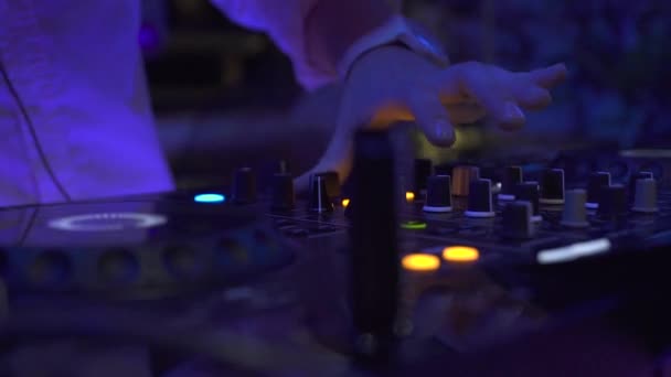 Dj gece kulübü partisinde dans etkinliğinde ses konsolunda müzik çalıyor. Dj mixer çalar ve disko parti için müzik konsolu. Renkli ışıklı disk jokey paneli ve karıştırma güverte. — Stok video
