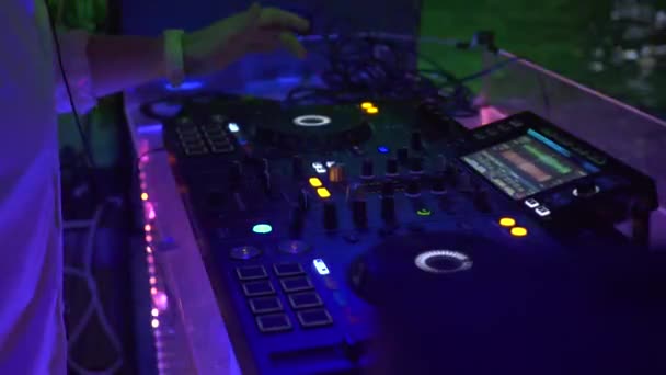 Ελεγκτής DJ και κονσόλα μουσικής σε πολύχρωμο φως σε πάρτι χορού στο νυχτερινό κέντρο διασκέδασης. Player μίξερ και κονσόλα ήχου για ντίσκο πάρτι. Δίσκος ταμπλό και κατάστρωμα ανάμιξης με έγχρωμο φωτισμένο. — Αρχείο Βίντεο