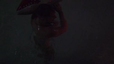 Gece havuzu partisinde köpekbalıklarıyla eğlenen genç bir adam. Açık hava yaz gece kulübündeki su partisinde ıslak adam. Gece hayatı konsepti.