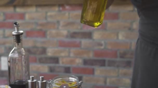 Cook hälla olivolja från glas flaska medan Matlagning mat på kök. Man hälla olivolja samtidigt förbereda hälsosam mat på restaurangkök. — Stockvideo