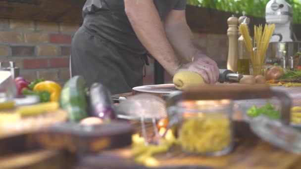 Чоловік кухар замішувати тісто для макаронів на кухні. Шеф-кухар робить тісто на дерев'яний стіл для італійської піци. Процес виготовлення домашніх кондитерських виробів. Кулінарія хлібобулочні вироби, Продовольча концепція. — стокове відео