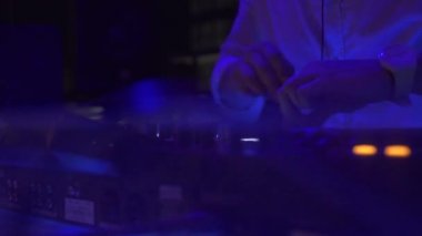Man Dj gece kulüp partisinde ses konsolunda dans müziği çalıyor. Gece kulübünde müzik ve renkli ışık karıştırma için Dj denetleyicisi. Disk jokey güverte ve dans partisinde karıştırma konsolu.