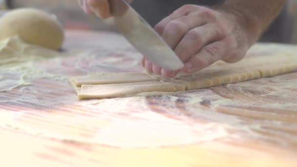 Processo di primo piano facendo pasta fatta in casa. Cuoco cuoco taglio con coltello pasta fresca per pasta tradizionale italiana a nastro sottile. Ricetta cucina italiana. Cucina casalinga. Marito cucinare cibo in cucina . — Video Stock