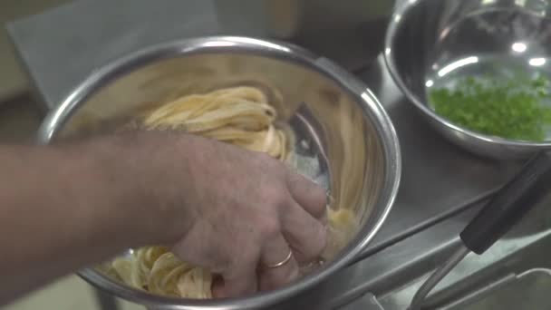 Z bliska gotowanie surowego makaronu we wrzącej wodzie w kuchni restauracji. Ręka szefa kuchni gotować wprowadzanie świeżego makaronu w gorącej wrzącej wody. Gotowanie potraw tradycyjnej kuchni włoskiej. — Wideo stockowe