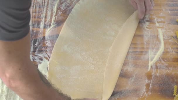 Mains masculines préparant la pâte fine pour les pâtes italiennes fraîches à la vue de dessus de table en bois. Chef cuisinier faire de la pâte pour les pâtes fraîches par recette traditionnelle. Concept de nourriture maison. Cuisine italienne . — Video