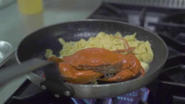 Cangrejo rojo y pasta italiana cocinando en sartén sobre fuego de estufa en la cocina. Chef espolvorear condimento sobre pasta italiana con mariscos en la sartén en la cocina del restaurante. Cocinar espaguetis con mariscos frescos . — Vídeos de Stock