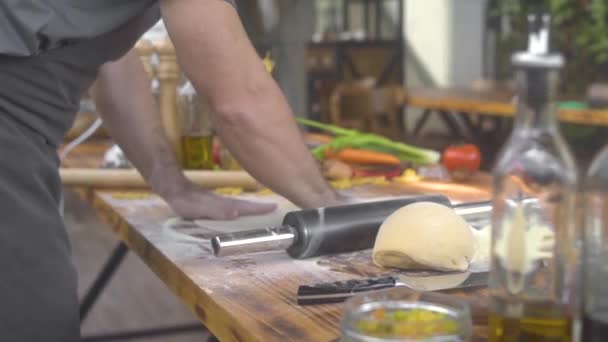 Chef szakács permetezés lisztet pizza tésztát, miközben gördülő hengerrel. Az olasz étteremben tésztát készítünk friss tésztákhoz. Főzés házi készítésű péksütemények, torta és a pite. Egészséges, házias ételek. — Stock videók