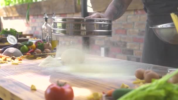 Chef-kok gieten meel poeder door zeef voor het kneden van deeg. Man zeven bloem op tafel terwijl het maken van deeg op de keuken. Voorbereiding Italiaanse pasta. Traditionele gerechten koken. — Stockvideo