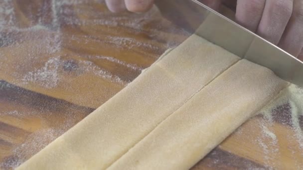 男性手工切割自制意大利面面团用刀在木板上。厨师用传统的意大利食谱制作新鲜的意大利面面团。意大利美食食谱。烹饪手工食品. — 图库视频影像