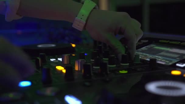 Manos masculinas en la consola de sonido dj mezclando música house en la fiesta nocturna. Controlador DJ para mezclar música y luz colorida en discoteca. Panel de jinete de disco y ecualizador de sonido de cerca . — Vídeo de stock