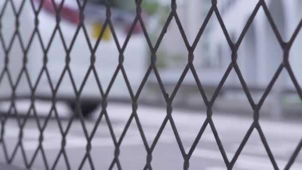 Tráfico de coches en la carretera de la ciudad a través de malla de valla. Vista a través de malla de valla de alambre en coche y taxi de conducción en la carretera urbana en la ciudad moderna . — Vídeo de stock