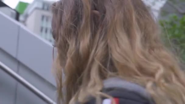 Scuotendo la faccia di sparatoria la giovane donna che sale le scale in parco urbano moderno. Close up viso riccio donna dai capelli rossi che sale per le scale sulla strada urbana nella città sviluppata . — Video Stock