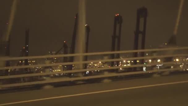 Shaking shooting from driving car on night city highway past sea repair port. View from window driving car to industrial shipyard in sea port and buildings in modern city. — Stock Video
