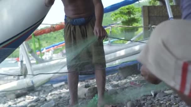 Bali, Indonesia - Mayo, 2019: pescador saludando con las manos y mostrando la captura de peces en la orilla del mar. Pescadores consiguiendo la captura de peces por la red de pesca en barco en agua de mar . — Vídeos de Stock