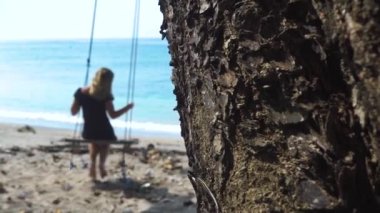 Mutlu kadın mavi deniz suyu ve kertenkele ağaç gövde arka plan üzerinde sürünerek sahilde salıncak sallanan. Tatil eğlencesi. Genç mutlu insanların yaşam tarzı. Tropik plaj yaşam tarzı. Yaz tatili.