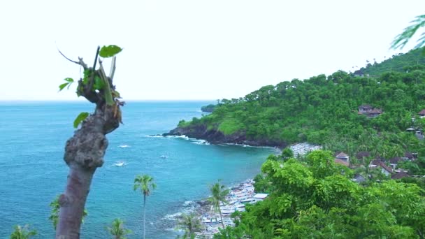 Barca da pesca tradizionale balinese a Bali Indonesia. Boa pescatore galleggiante in mare e in piedi sul parcheggio sulla spiaggia di sabbia. Cliff e verde paesaggio montano . — Video Stock