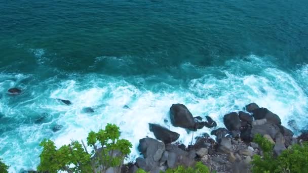 Морские волны сокрушаются до скалистой скалы с брызгами и белой пеной. Океанские волны выплескиваются на скалистую вершину острова. Бирюзовый морской серфинг на каменистом фоне пляжа . — стоковое видео