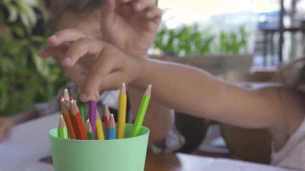 Anak laki-laki dan perempuan mengambil pensil warna untuk menggambar di kertas. Kakak dan adik menggambar dan mewarnai dengan pensil berwarna-warni. Anak-anak menghabiskan waktu bersama . — Stok Video