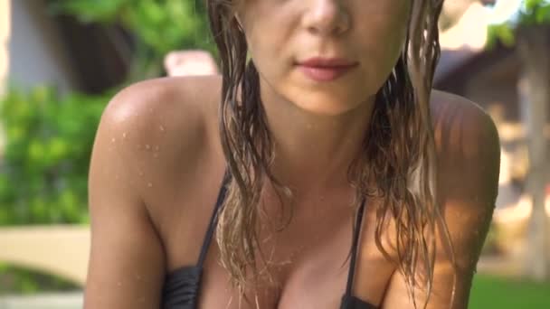 Yaz lık tatil beldesinde yüzme havuzunda ıslak saçlı ve bikinili güzel bir kadın portresi. Güneşli bir günde güneş ışığı altında ön kameraya bakan ve poz veren çekici bir kadın. — Stok video