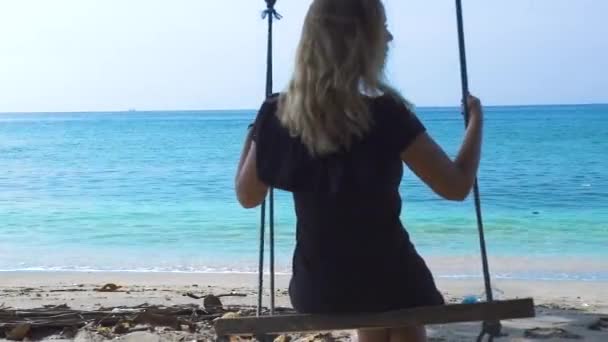 Donna felice sull'altalena sulla spiaggia di mare. Giovane ragazza che oscilla su altalena sulla spiaggia durante le vacanze estive. Divertirsi durante le vacanze estive. Giovani persone felici stile di vita. Stile di vita tropicale spiaggia . — Video Stock