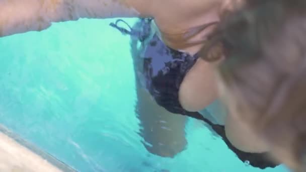 Sexy Frau im schwarzen Bikini posiert in blauem Wasser Außenpool im Sommerferienhotel. Gesicht schöne Frau entspannen im Schwimmbad in den Sommerferien. Fröhliche Urlaubsfreizeit. — Stockvideo