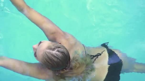 Jovem mulher de biquíni preto nadando na piscina do hotel resort. Mulher bonita relaxando na piscina nas férias de verão. Feliz lazer de férias . — Vídeo de Stock