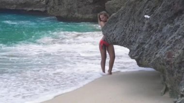 Şehvetli kadın kayalık plaj ve deniz dalgaları arka planda poz. Mayo yaz plajda dinlenmek çekici kadın. Tropikal tatil. Tatil yaşam tarzı.