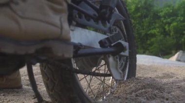 Motosikletli motosikletli yeşil dağlarda kumlu yolda kayma. Yaylalarda kumlu yolda motosikletle araba kullanan turist. Moto seyahati. Motosiklet yaşam tarzı.