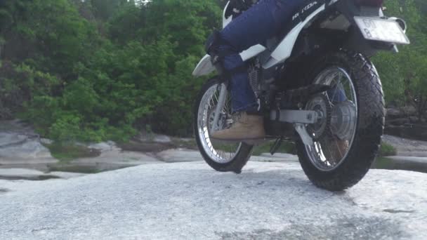 Мотоциклист слезает с мотоцикла в горах. Турист, путешествующий на мотоцикле по скалистым горам. Мото путешествия. Мотоцикл — стоковое видео