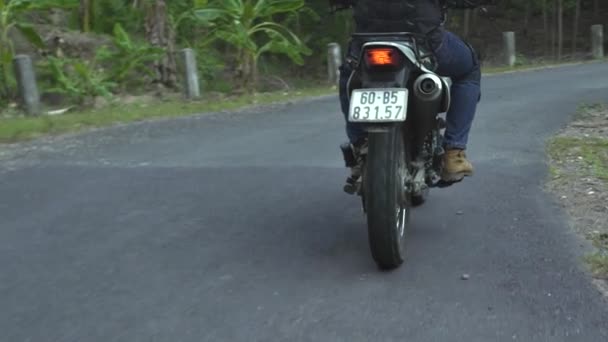 Мотоциклист едет на мотоцикле по дороге во время мотопутешествия. Байкер едет на мотоцикле по проселочной дороге. Путешествие на мотоцикле. Мото стиль жизни — стоковое видео