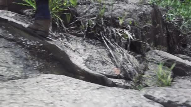 Męska stopa stepping na kamieniu w płynie rzeka z górskiego wodospadu. Męska stopa w butach spacerowych wzdłuż skalistej górskiej rzeki w podróży. Podróże, trekking i turystyka. — Wideo stockowe