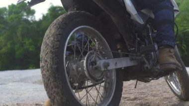 Motosikletli motosikletli yeşil dağlarda kumlu yolda kayma. Yaylalarda kumlu yolda motosikletle araba kullanan turist. Moto seyahati. Motosiklet yaşam tarzı.