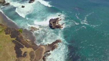 Yazın kayalık kıyı şeridinde kopan okyanus dalgalarının yukarıdan görünüşü..