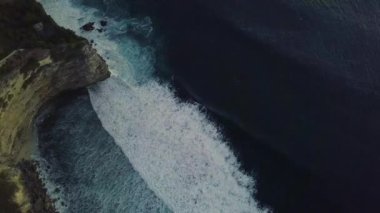 Görkemli beyaz sörf dalgaları mavi okyanusta hareket ediyor ve kırılıyor.