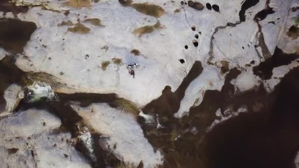 Keringő légi felvétel egy férfi kerékpárral ül kövezett kő a folyóban. — Stock videók