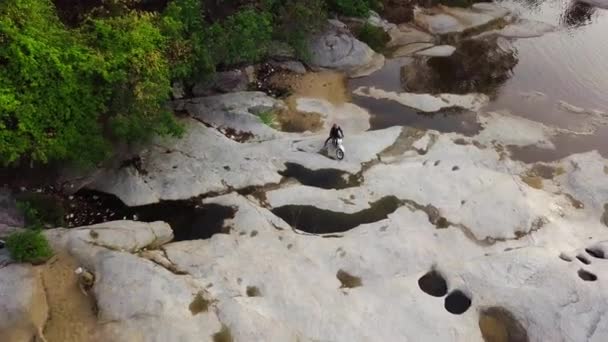 Повітряний постріл велосипедиста, який перетинає скелясту річку в горах.. — стокове відео