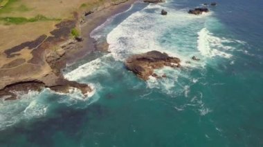 Yazın kayalık kıyı şeridinde kopan okyanus dalgalarının yukarıdan görünüşü..