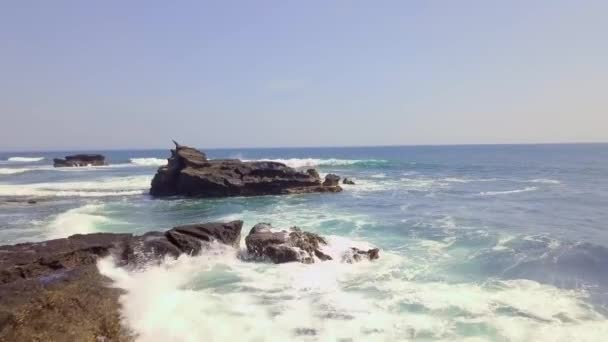 Pemandangan udara di atas pantai berbatu dan lautan biru bergelombang. Gelombang putih menerjang. — Stok Video