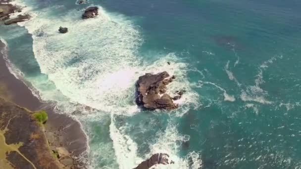 Vista aérea sobre una costa rocosa y un océano azul ondulado. Olas blancas estrellándose . — Vídeos de Stock