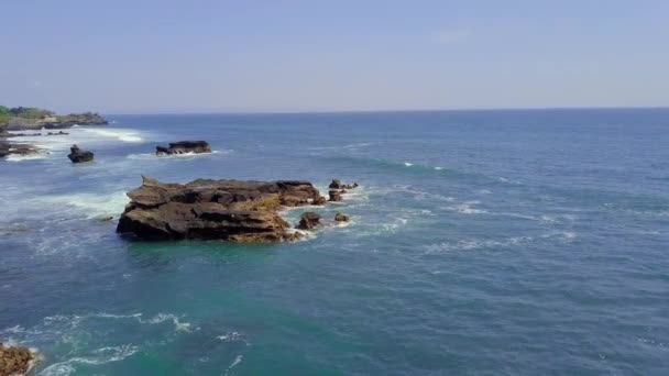 Vista aerea su una spiaggia rocciosa e un oceano blu ondulato. Onde bianche che si infrangono . — Video Stock