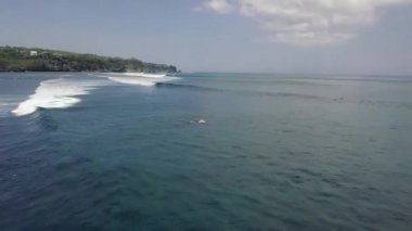 Dalgalar ve sörfçülerin yüzdüğü tropikal okyanusun üzerinde uçan hava..